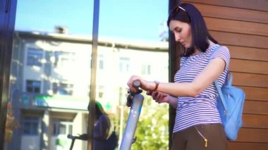 Genç kız onun elinde bir telefon ile elektrikli scooter üzerinde döner ve yaprakları