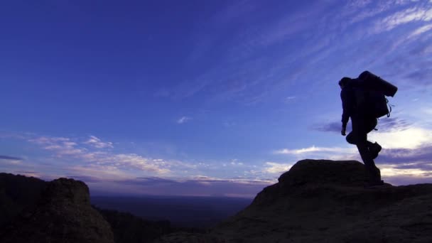 Young girl with a backpack on top of the mountain looking into the distance — Stock Video