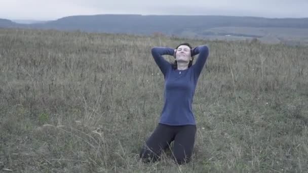 Expresiva chica de rodillas en la hierba está llorando y sosteniendo la cabeza, lento mo — Vídeos de Stock