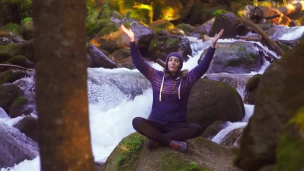 Fille assise sur une pierre au bord de la rivière et méditant, lent mo — Video