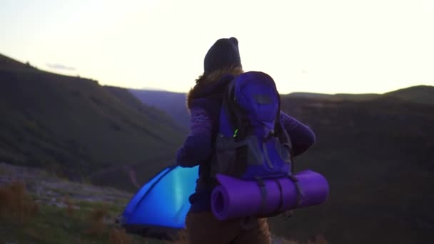 Woman with a hiking backpack behind at sunset returned to the tent — Stock Video