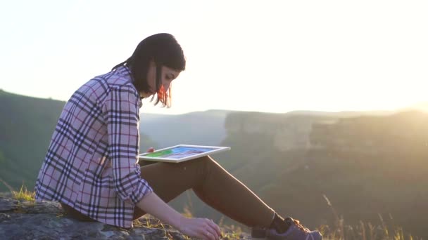 Meisje kunstenaar schildert een beeld van de bergen en de zonsondergang, langzame mo — Stockvideo