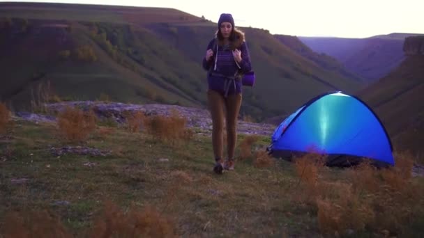 Кемпинг женщина с рюкзаком на закате ходьбы от палатки — стоковое видео