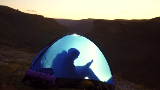 Одинокая женщина ночует в палатке он пользуется телефоном — стоковое видео