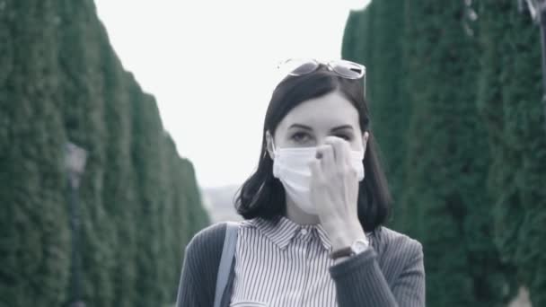 Meisje opstijgt een medische masker van haar gezicht en diep inhaleert de lucht in het park, langzame mo — Stockvideo