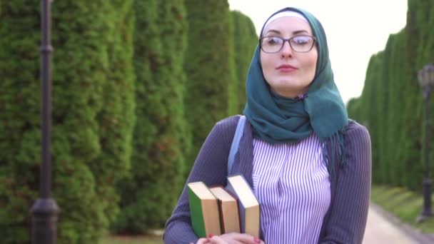 Muslim girl student with books into the park ,slow mo — Stock Video