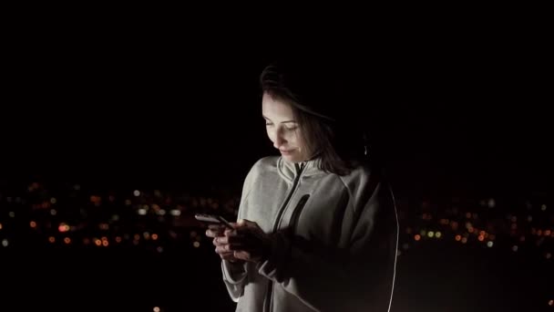 Hezká dívka používá telefon v noci na pozadí noční město, pomalé mo