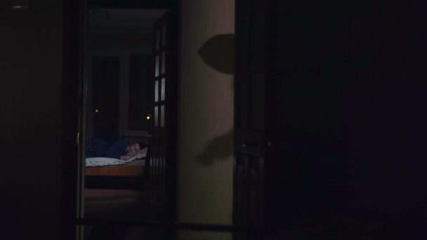 Maskovaný lupič s baterkou v ruce vstoupil do bytu, kde dívka spí — Stock video