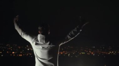 Erkek kazanan duruş kollarını gece şehrin arka planı yaymak