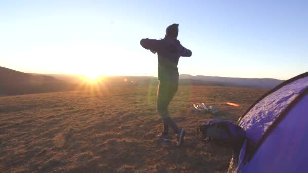 Молодая кемпинговая женщина с открытыми руками выходит из палатки на закате — стоковое видео