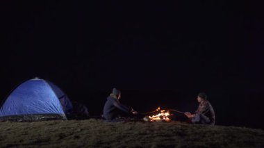 Geceleri oturup bir yangın dağlarda turist çadır ve yavru Marshmallow
