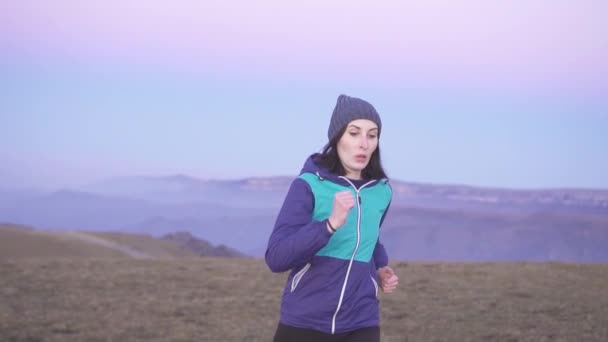 Porträtt av kvinna idrottsman kör vid solnedgången i bergen, långsamma mo — Stockvideo