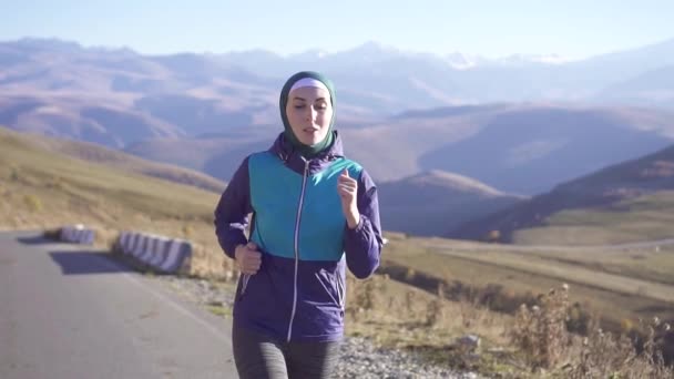 Araberin im Hijab rennt auf Sonnenbergstraße zurück Bergblick, langsam — Stockvideo