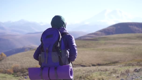 Junge arabische Frau mit Touristenrucksack unterwegs auf einer Bergstraße, langsam — Stockvideo