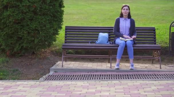 Meisje met visuele handicap in het Park leest een boek met Braille met haar vingers — Stockvideo