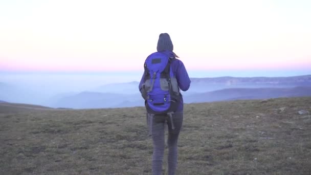Vrouw toerist met een rugzak op zijn rug is op de achtergrond van bergen, achteraanzicht — Stockvideo