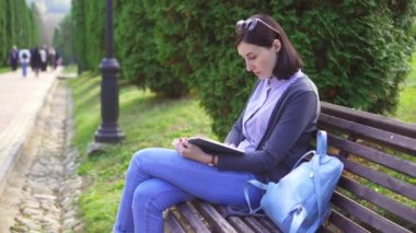 Bir bankta okuma dizlerinin üzerine bir kitap ile kız