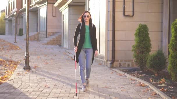 Joven mujer ciega con una mochila con un bastón pasa por la ciudad rayos de sol, lento mo — Vídeos de Stock