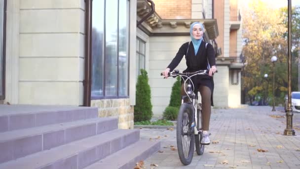 Молода мусульманка в хіджабі їде на велосипеді — стокове відео