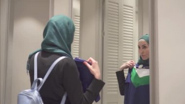 Bir ayna önünde giysilerindeki oldukça Müslüman kadın bir hijab ve bir sırt çantası ile çalışır