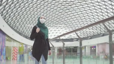 Bir sırt çantası ve tıbbi maske yüzünde bir hijab oldukça Müslüman kadın alışveriş, yavaş mo gider
