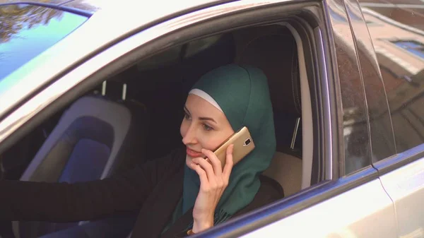 美丽的穆斯林妇女驾驶汽车在电话里微笑 — 图库照片