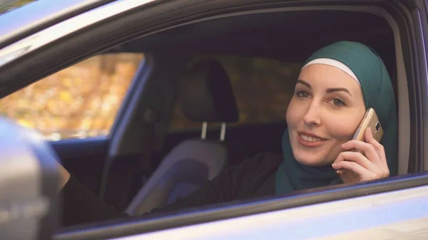 一个美丽的女司机在头巾的肖像与电话在车上 — 图库照片