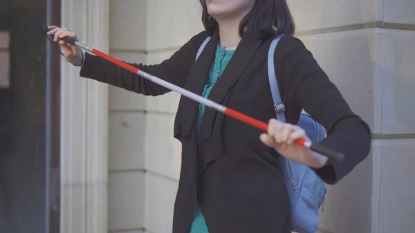 cane for the blind in the hands of a young stylish woman on the street