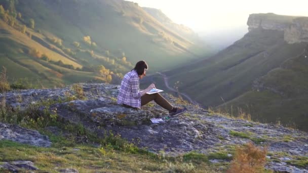Flicka konstnär målar en bild av berg och solnedgången med en borste, långsamma mo — Stockvideo