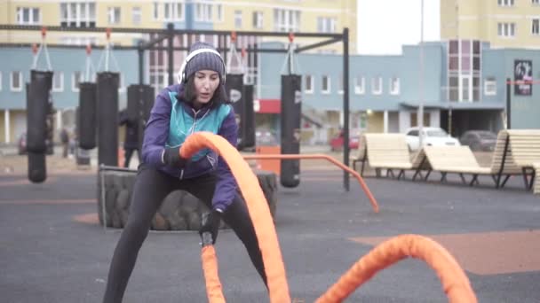 Vrouw atleet die zich bezighouden met crossfit met touwen op de straat speelplaats, langzame mo — Stockvideo