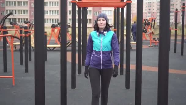 Woman athlete with headphones on the street playground — Stock Video