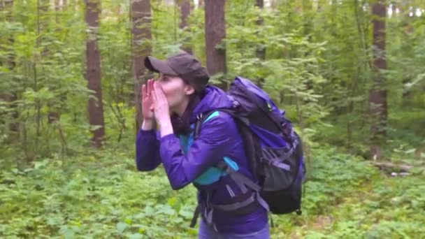 Растерянная женщина в панике с рюкзаком, потерявшаяся в лесу, зовущая на помощь — стоковое видео