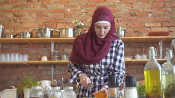 Jeune femme musulmane dans la cuisine coupe des légumes pour cuisiner des aliments — Video