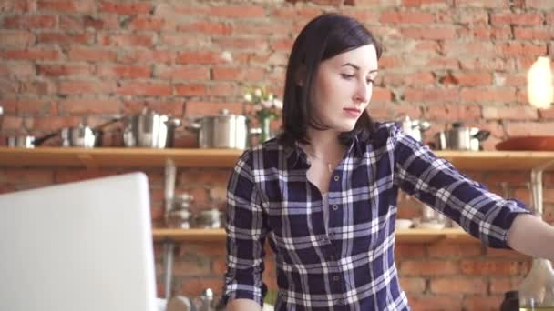 Женщина на кухне смотрит на ноутбук рецепт посуды в руках овощи — стоковое видео