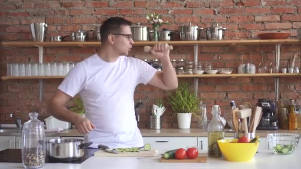 Ritratto di un giovane che balla e canta in cucina, taglia verdure — Video Stock