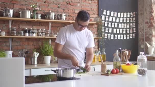 L'homme coupe des légumes dans la cuisine et éprouve un mal de tête aigu, il attrape sa tête — Video