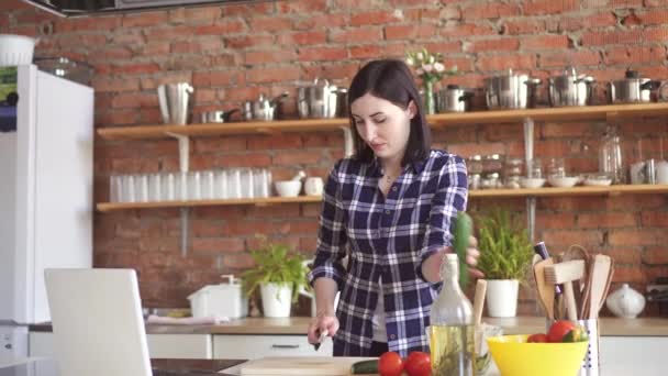 料理を調理する方法台所でのラップトップのビデオ チュートリアルを見ている女性 — ストック動画