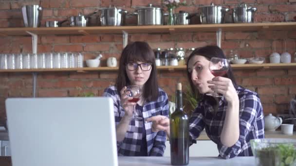 Dos chicas novias en camisas a cuadros en la cocina bebiendo vino y viendo el cuaderno — Vídeos de Stock