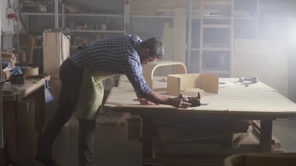 menuiserie homme en chemise plane un arbre dans un atelier sombre authentique 