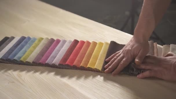 Samples of colored fabric for making furniture in the hands of a bearded man in an authentic workshop — Stock Video