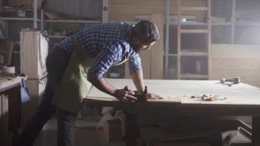 profesyonel erkek ben marangoz ahşap bir karanlık otantik atölyede planya gömlek