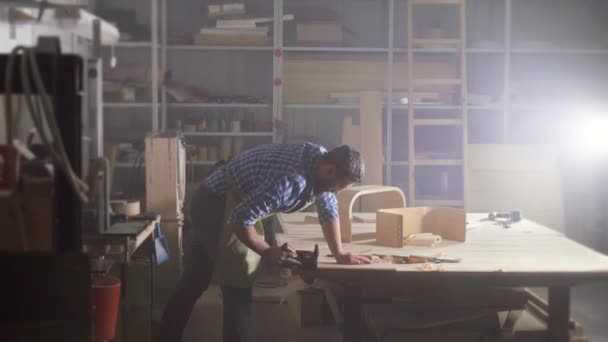 kraftman un homme avec une barbe dans une chemise dans l'atelier plane un arbre avec des copeaux 