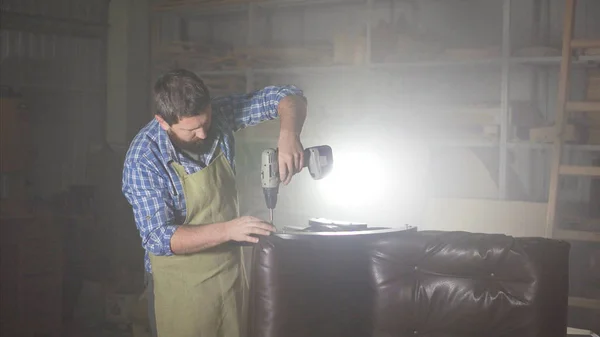 bir adam bir sakallı apronda karanlık bir otantik atölye montaj mobilya yapan