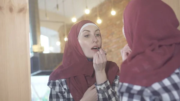 年轻漂亮的穆斯林妇女在一个头巾在镜子油漆 — 图库照片