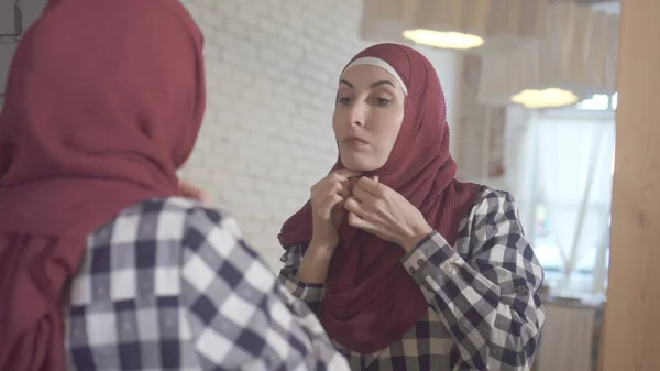 一个年轻的穆斯林妇女在镜子前戴围巾的肖像 — 图库照片