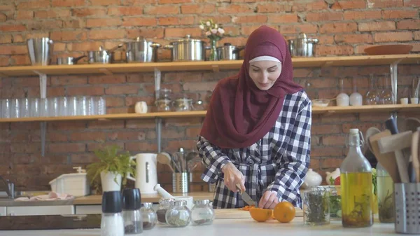 纵向穆斯林年轻女子在厨房削减蔬菜 — 图库照片