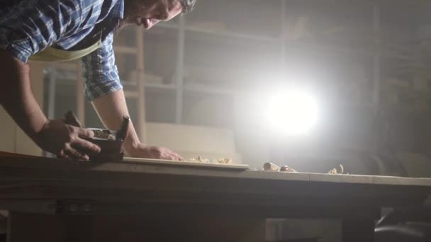 Retrato carpintero masculino en camisa en madera cepillada taller oscuro — Vídeo de stock