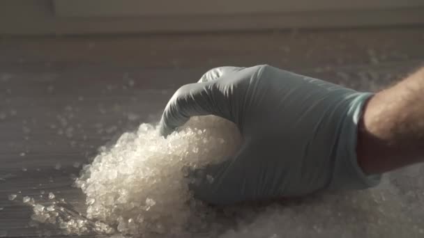 Goutte de gel de silice blanche avec les mains en gants bleus — Video