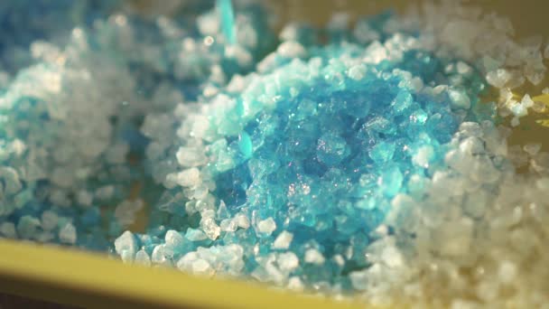 Pohled na spoustu bílých krystalů Silika gel absorbuje modré vody — Stock video