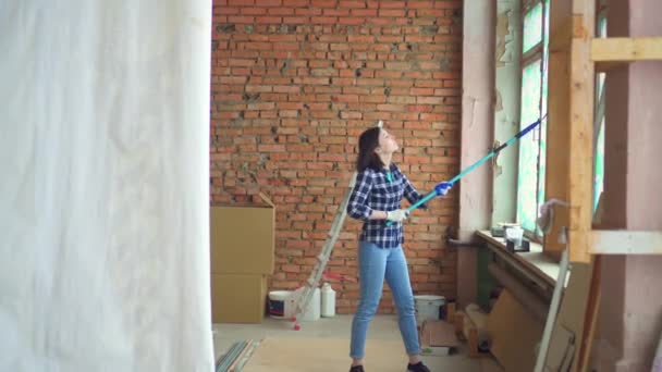 Retrato de una hermosa chica en una camisa a cuadros hace-it-yourself reparaciones en el apartamento — Vídeo de stock